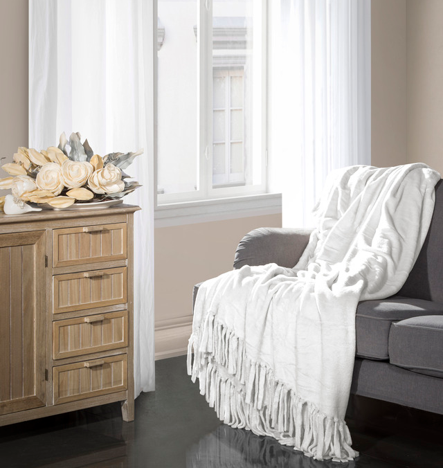 Biała nowoczesna narzuta na kanapę do salonu z dekoracyjnymi frędzlami